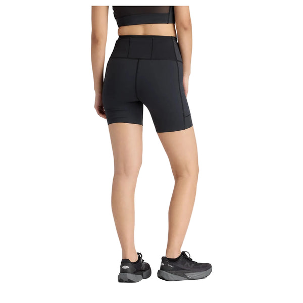 En person iført sort sports-bh, New Balance RC Elite Storage Short 6" Dame i sort og sorte løbesko står med ryggen til og viser bagsiden mod en almindelig hvid baggrund.