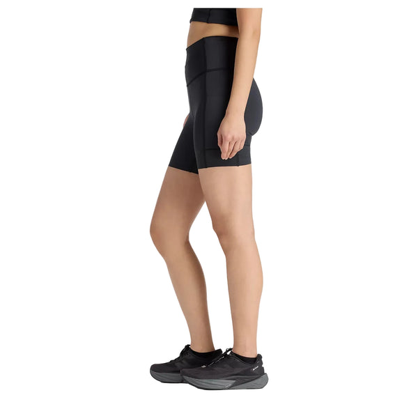 En person ses i profil iført sort sports-bh, sort New Balance RC Elite Storage Short 6" Dame og sorte sportssko på en hvid baggrund.