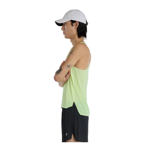 En person i profil med korslagte arme bærer en hvid kasket, sorte shorts og New Balance Race Day Ultra Light Singlet, Herre, Afterglow. Baggrunden er helt hvid.