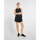 En kvinde står på en ensfarvet baggrund iført sort New Balance Race Day Ultra Light Singlet, Dame, sorte shorts og løbesko. Løbesinglettens NB ICE-teknologi sikrer overlegen komfort til langdistanceløb.