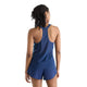 En person med mørkt, skulderlangt hår ses bagfra iført New Balance Race Day Ultra Light Printed Singlet, Dame, Altitude – en blå tanktop med racerryg – kombineret med matchende blå sportsshorts foran en ensfarvet hvid baggrund, hvilket illustrerer den strømlinede stil i New Balance Race Day-løbetøj til kvinder.