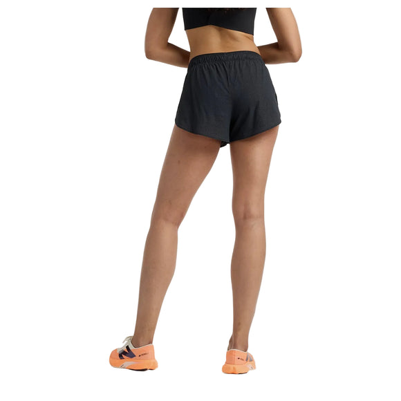 En kvinde står med ryggen til kameraet iført en sort crop top, New Balance Rc Ultra Light Split Short 3" Dame i sort og orange sportssko med hvide såler på en almindelig hvid baggrund.