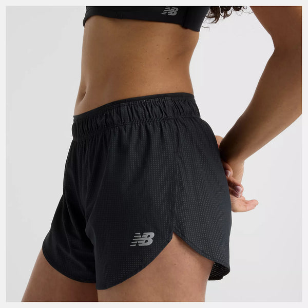 Person iført sort sports-bh og New Balance Rc Ultra Light Split Short 3" dame i sort med NB DRY-teknologi. Kun overkroppen og overbenene er synlige mod en almindelig lys baggrund, med den ene arm bøjet bag ryggen.