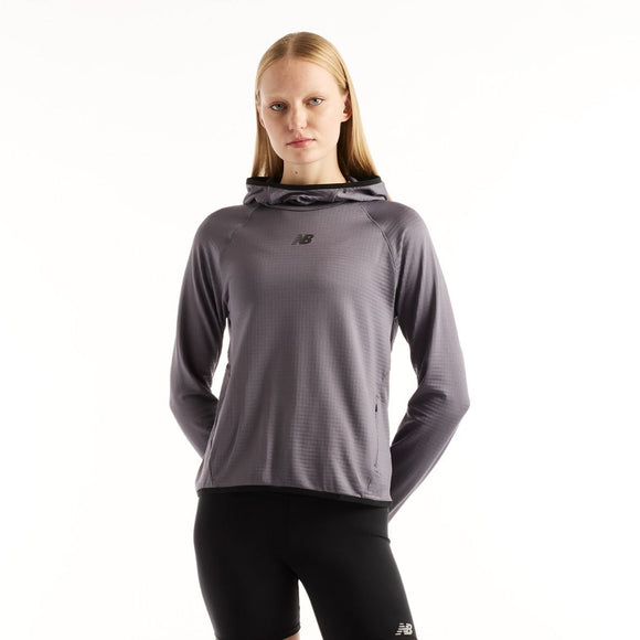 En person har en grå New Balance Rc Essential Heat Grid-hoodie med gittermønster på, Dame, Neptune Grey, på sammen med sorte leggings.