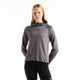 En person har en grå New Balance Rc Essential Heat Grid-hoodie med gittermønster på, Dame, Neptune Grey, på sammen med sorte leggings.