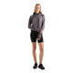 En kvinde iført en New Balance Rc Essential Heat Grid-hoodie i farven Neptune Grey med tommelfingerhuller, sorte sportsshorts og sorte sneakers.