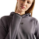 En person, der har en grå New Balance Rc Essential Heat Grid-hoodie på med et sort logo på brystet.