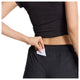 En person iført New Balance Rc Short 5", Dame, Sort er i færd med at lægge et kort i lommen med lynlås i linningen på disse svedtransporterende løbeshorts, mens vedkommende har en sort top på.