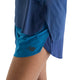 Et nærbillede af en person, der bærer blå New Balance Rc Ultra Light Printed Short 3″, Dame, Altitude, kombineret med en matchende blå top. Kun underkroppen og lårene er synlige på en hvid baggrund, hvilket fremhæver det elegante design af disse ultralette løbeshorts til kvinder.