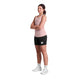 En person står med armene over kors iført Saysky Reactive Flow Singlet, Dame, Pink Logo, sorte sportsshorts, hvide strømper og hvide sportssko. Den enkle hvide baggrund giver perfekt løbetøjsinspiration til løbsdagen.