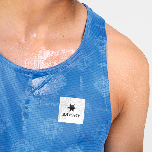 Nærbillede af en persons øvre bryst og skulder, iført Saysky Reactive Flow Singlet, Herre, Blue Aop. Huden og singletten er våde – sandsynligvis af sved – hvilket understreger den optimale svedtransport i denne ultralette top. Det hvide Saysky-logo er synligt på singletten.