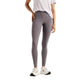 Der ses en person fra skuldrene og ned, iført en hvid kortærmet skjorte, hvide sportssko og et par New Balance Reflective Rc Heat Legging 27″ til kvinder i farven Neptune Grey. Leggingsene med høj talje har reflekterende detaljer og sidelommer. Baggrunden er ensfarvet hvid.