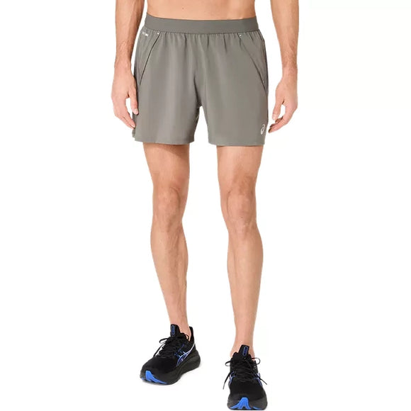 Der vises et billede af en person fra livet og ned, iført Asics Road 5In Shorts, Herre, i farverne Truffle Grey og sorte løbesko, på en ensfarvet hvid baggrund.