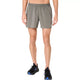 Der vises et billede af en person fra livet og ned, iført Asics Road 5In Shorts, Herre, i farverne Truffle Grey og sorte løbesko, på en ensfarvet hvid baggrund.