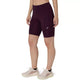 En person har Asics Road High Waist 8In Sprinter-shorts i farven Dark Aubergine og lyserøde sportssko på, og billedet viser vedkommende fra taljen og ned mod en hvid baggrund.