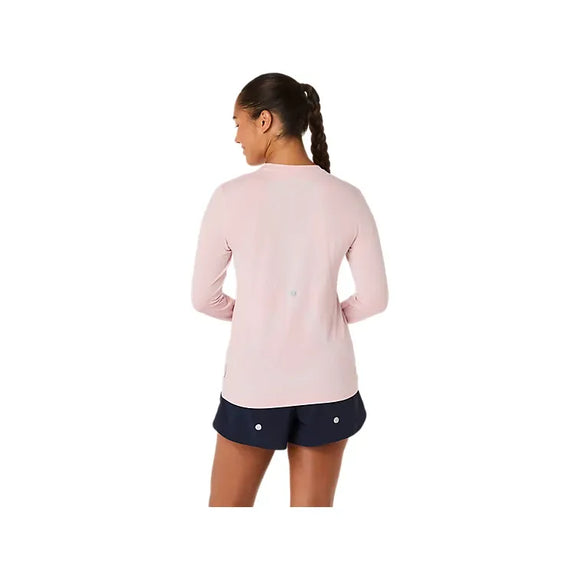 En kvinde med en lang fletning ses bagfra iført Asics Road Seamless LS Top, Dame in Morganite/Dusty Red og marineblå shorts med hvide knapper, stående på en almindelig hvid baggrund.