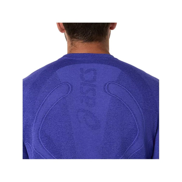 Billedet viser bagsiden af en person iført Asics Road Seamless LS Top til mænd i Cobalt Burst/Eggplant, med "ASICS" og mærkets logo vævet på den øverste del af ryggen og i nakken. Kun denne del af toppen er synlig.