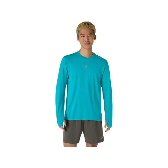 En person står med ansigtet vendt fremad og har ASICS Road Seamless LS Top til mænd i farven Energy Aqua på – en åndbar langærmet trøje med et lille logo på brystet – samt mørkegrå sportsshorts. Baggrunden er ensfarvet hvid.