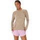 En person står med ansigtet vendt fremad iført en gråbeige Asics Road Seamless SS Top, Dame, og lyserøde sportsshorts foran en ensfarvet hvid baggrund.