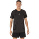 En mand står vendt fremad iført en Asics Road Seamless Ss Top, Herre, i farven Performance Black med et diskret mønster og logo på brystet, kombineret med sorte sportsshorts på en ensfarvet hvid baggrund.