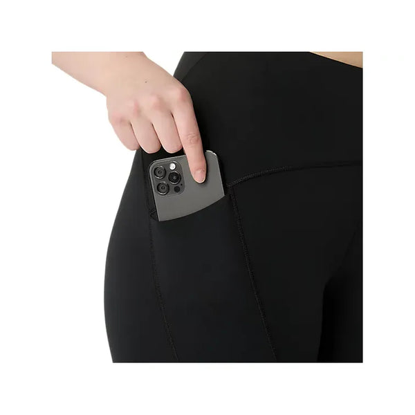En person lægger en smartphone i sidelommen på et par sorte Asics Road Winter High Waist Tights, Dame, Performance Black, hvor kun vedkommendes hånd, hofte og øvre lår er synlige på en hvid baggrund.