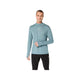 En mand står foran en hvid baggrund iført Asics Road Winter Seamless Ls Top til mænd i farven »Foggy Teal«, der er fremstillet af termisk materiale med tommelfingerhuller i ærmerne og et lille logo på brystet. Trøjen er designet som en sømløs vinterløbetrøje og giver optimal komfort i koldt vejr. Han har den på sammen med sorte bukser.