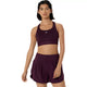 En person med mørkt hår af mellemlang længde og et neutralt udtryk står med blikket rettet fremad og har en Asics Road Compression Bra til kvinder i farven Dark Aubergine på, som har et lille logo i midten.