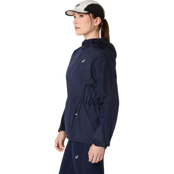 En kvinde i profil bærer Asics Road Packable Jacket, Dame, Midnight med hætte og matchende leggings. Hun sætter den sammen med en sort og hvid kasket og har håret sat op i en hestehale. Det miljøvenlige outfit er lavet af genbrugsmaterialer.