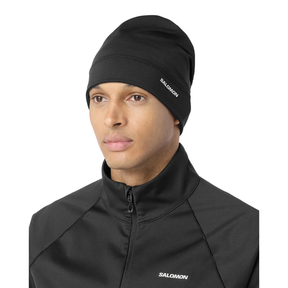 Person iført en sort Salomon Run Tech Beanie, unisex, Deep Black med logo på siden, velegnet til vinterløb.