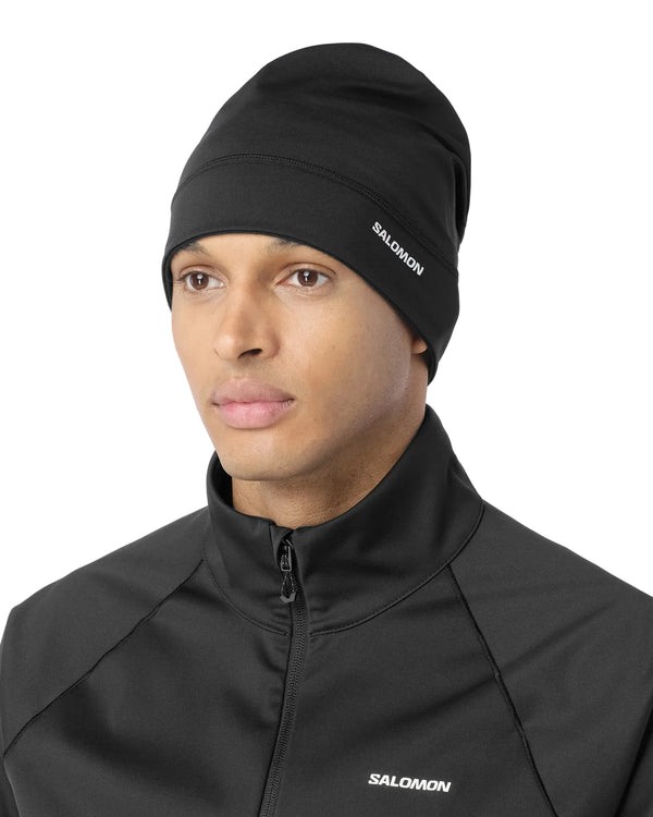 Person iført en sort Salomon Run Tech Beanie, unisex, Deep Black med logo på siden, velegnet til vinterløb.