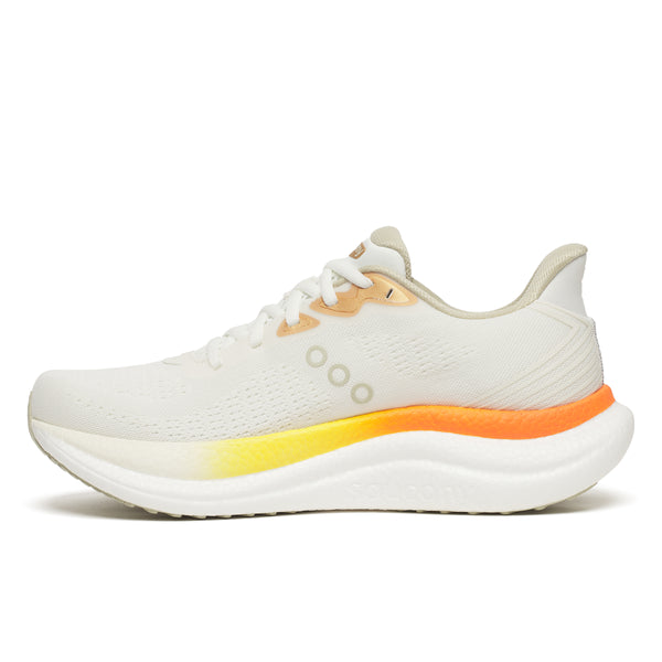 Saucony Triumph 23, Herre, Ivory/Fire er en hvid sportssneaker med overdel i mesh, beige detaljer, hvide snørebånd og en tyk sål, der går over i gult og orange ved hælen - designet til maksimal komfort. Vist fra siden på en almindelig hvid baggrund.