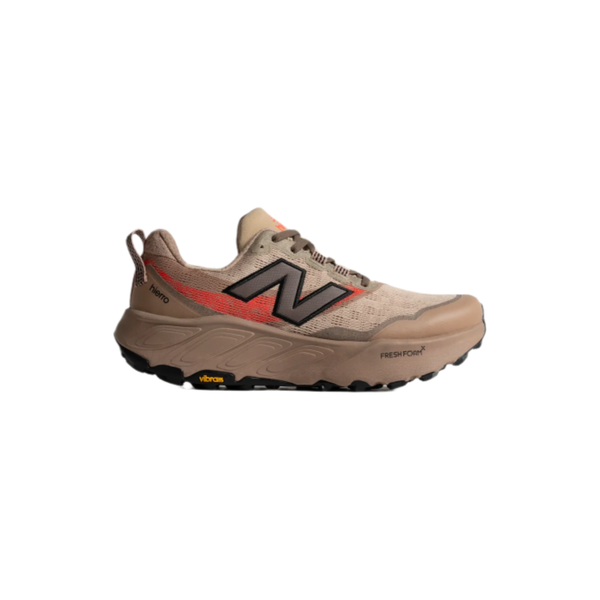 New Balance Freshfoam Hierro V9 Herre i Desert Clay har et solbrunt og rødt design med et sort N-logo, en robust Vibram Megagrip-sål og Fresh Foam X-label nær tåen, vist på en hvid baggrund.