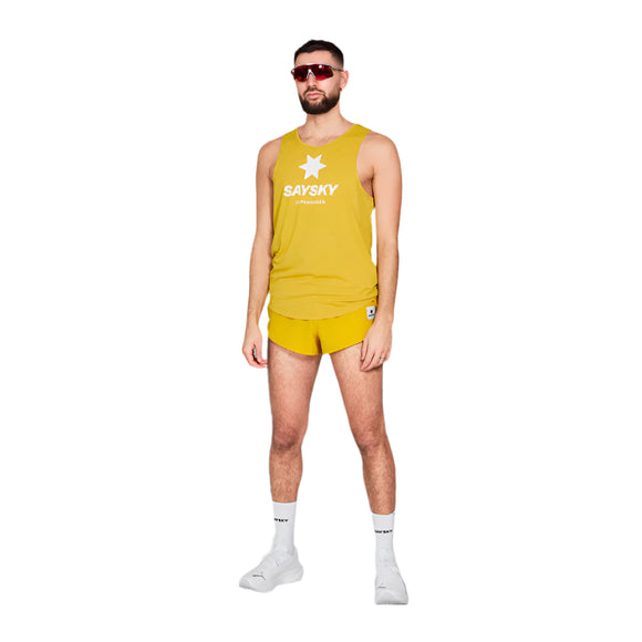 En mand i en gul Saysky-tanktop med en stjerne og et logo foran og matchende Combat Shorts 2", Herre, står med ansigtet vendt fremad. Han har kort hår, solbriller, hvide sokker og sneakers.