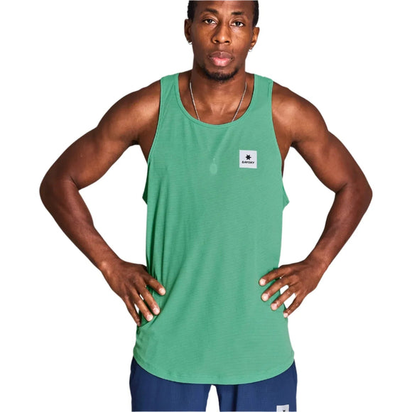 En mand står med hænderne på hofterne iført en grøn Saysky Reactive Flow Singlet, Herre, Green Aop fremstillet af genbrugspolyester og mørkeblå shorts. Singletten har et lille hvidt rektangulært logopatch på venstre bryst.