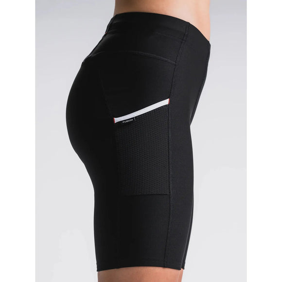 En person bærer Fusion's Short Tights Advanced, Unisex, i Superblack - udstyret med en struktureret sidelomme og et lille hvid-rødt mærke - ideel til træning eller løb, set fra siden mod en ensfarvet baggrund.