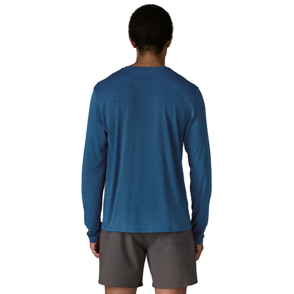 En person står med ansigtet vendt mod kameraet iført en Patagonia Long-Sleeved Capilene Cool Daily Shirt, Herre, Clement Blue - Light Clement Blue X-Dye mod en almindelig lys baggrund.