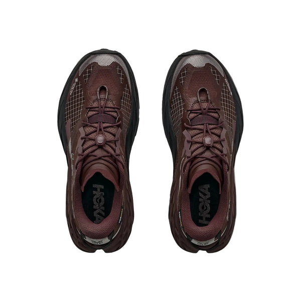Et par Hoka Speedgoat 7 GTX damesko i farven Deep Mauve/Black ses set ovenfra. Disse trailsko har en overdel af åndbart mesh, mønstrede overlag og snørebånd med træknapper og er udstyret med GORE-TEX-teknologi, der sikrer beskyttelse mod vejr og vind. Hoka-logoet er synligt på indersiden af hver sko.