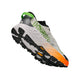 Hoka Speedgoat 7 til mænd i farvekombinationen Frost / Neon Tangerine er en atletisk trailsko med en kraftig sort Vibram Megagrip-sål, der sikrer fremragende greb, med et orange og gult farveforløb på siden, grønne og sorte detaljer samt mærkenavnet »HOKA« tydeligt fremhævet med store grønne bogstaver. Skoen er afbildet i en opadgående vinkel.