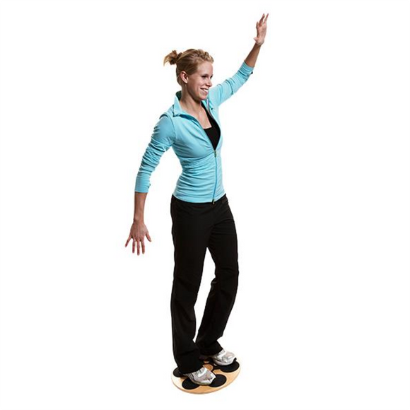 En person i en lyseblå jakke og sorte bukser balancerer på et Sports Pharma Wobbleboard (unisex med justerbar sværhedsgrad), med den ene arm løftet og den anden strakt ud til siden, foran en hvid baggrund.