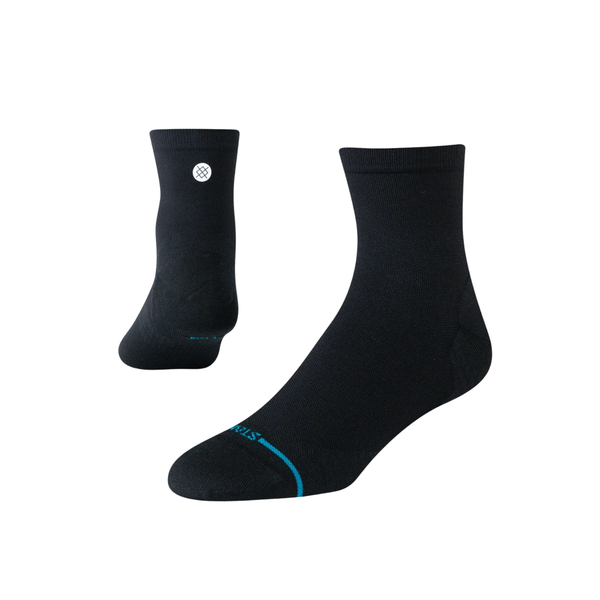 Stance Solid UL Quarter unisex løbestrømper i sort har et lille hvidt cirkulært logo på siden og en tynd blå linje nær tæerne, vist mod en almindelig hvid baggrund.