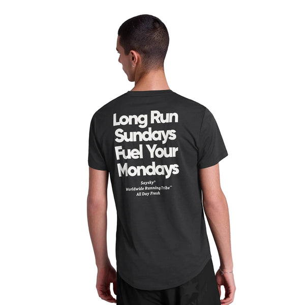 En person med kort hår kigger væk iført Saysky Statement Combat Pro T-shirt, Herre, Black med fed hvid "Long Run Sundays Fuel Your Mondays"-tekst på bagsiden - ideel til dedikerede løbere.