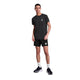 En person står på en hvid baggrund iført Saysky Statement Combat Pro T-shirt, Herre, Black - ideel til løbere, der har brug for en åndbar trænings-t-shirt. De kombinerer den med sorte shorts, hvide sokker og sorte sko, mens de kigger fremad med den ene hånd i lommen.