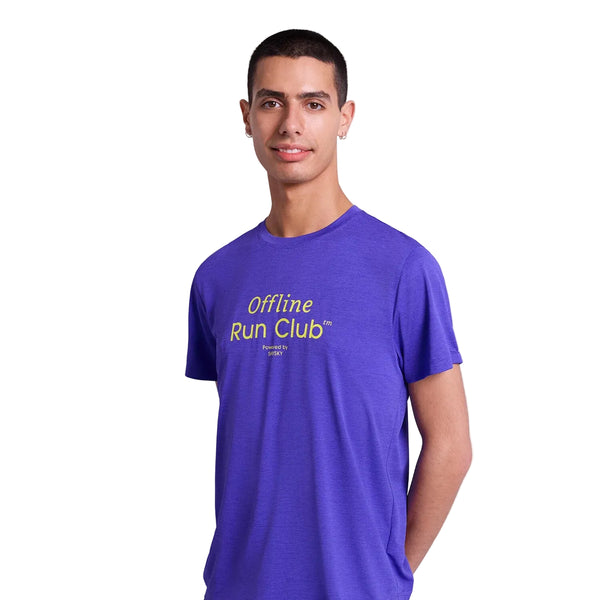 En mand med kort mørkt hår står på en almindelig hvid baggrund iført Saysky Statement Combat Pro T-shirt, Herre, Purple, med gul "Offline Run Club"-tekst. Denne åndbare sportstøj er designet til komfort.