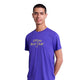 En mand med kort mørkt hår står på en almindelig hvid baggrund iført Saysky Statement Combat Pro T-shirt, Herre, Purple, med gul "Offline Run Club"-tekst. Denne åndbare sportstøj er designet til komfort.