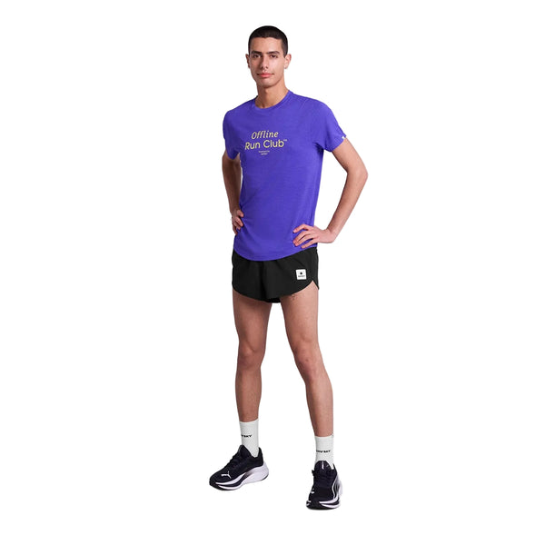 En person står med ansigtet fremad og en hånd på hoften iført en Saysky Statement Combat Pro T-shirt, Herre, Purple - perfekt åndbar sportstøj til enhver løbetur - plus sorte løbeshorts, hvide sokker og sorte sko på en hvid baggrund.