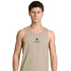 En mand med kort brunt hår har en Saysky Statement Combat Pro Singlet, Herre, Sand på, som er beige med SAYSKY-logoet og en blå stjerne på forsiden. Han står med ansigtet vendt mod kameraet foran en ensfarvet hvid baggrund med et neutralt udtryk. Singletten er kendt for sit hurtigtørrende materiale og fremragende åndbarhed, hvilket sikrer komfort under intens aktivitet.