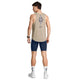 En mand står med ryggen til, iført en Saysky Statement Combat Pro Singlet, Herre, Sand – med et blåt motiv og tekst – kombineret med marineblå sportsshorts, hvide strømper med mørkeblå mønstre og hvide sneakers. Hans ærmeløse top er åndbar og hurtigtørrende, hvilket sikrer komfort under intense træningspas. Han har kort brunt hår og et ur på venstre håndled.