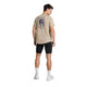 En mand står med ryggen til og har en Saysky Statement Combat Pro T-shirt (Herre, Sand) på med et lilla motiv på ryggen, kombineret med sorte shorts, hvide ankelstrømper og hvide sportssko. Baggrunden er ensfarvet hvid.