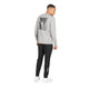 En mand står med ryggen til og har en grå Saysky Statement Pace Long Sleeve, Herre, på med et sort-hvidt motiv på ryggen, kombineret med sorte joggingbukser og hvide sneakers på en ensfarvet hvid baggrund. Det hurtigtørrende stof sikrer optimal komfort under alle former for aktivitet.