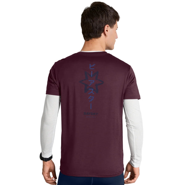 En mand står med ryggen til og har en Saysky Statement Pace T-shirt, Herre, i farven Burgundy på, over en hvid langærmet skjorte. T-shirten har et mørkt stjernemotiv og japanske tegn på ryggen, og nedenunder står der »SAFETY BEAST«.